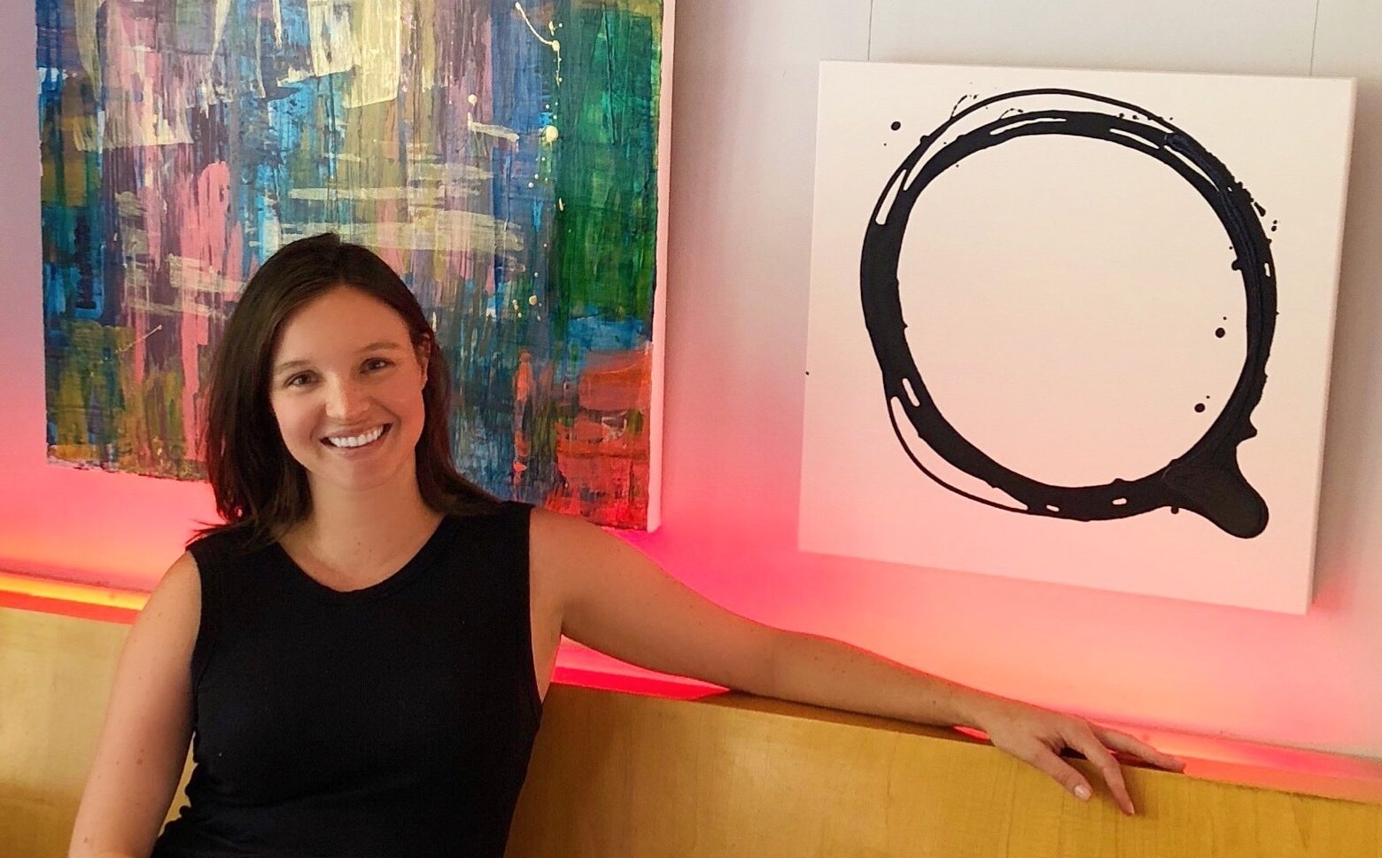 Caitlin Wheeler in front of original paintings installed at Peacock Cafe in Washington DC